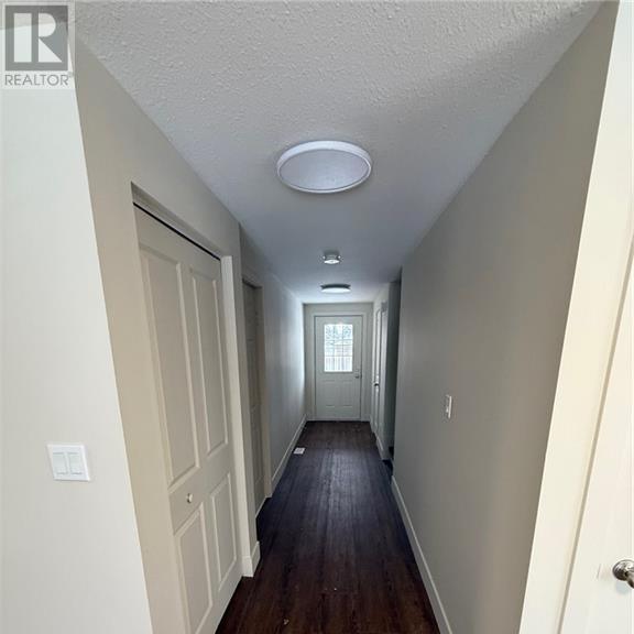 a long hallway with white walls and wood floors.