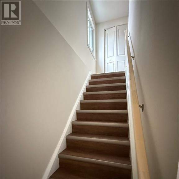 a staircase with a wooden handrail and brown steps.