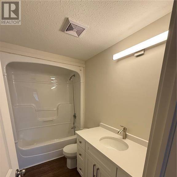 a white bathroom with a toilet, sink, and shower.
