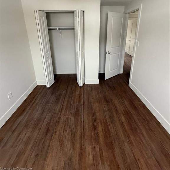 a room with wood flooring and a round mirror on the wall.