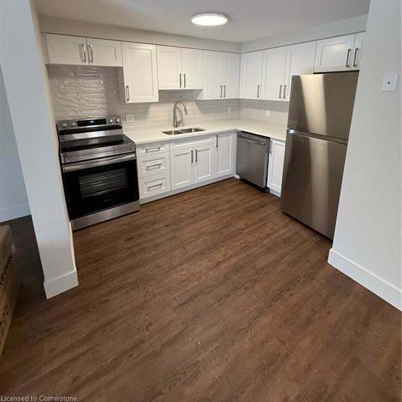 a kitchen with white cabinets and a wooden floor.