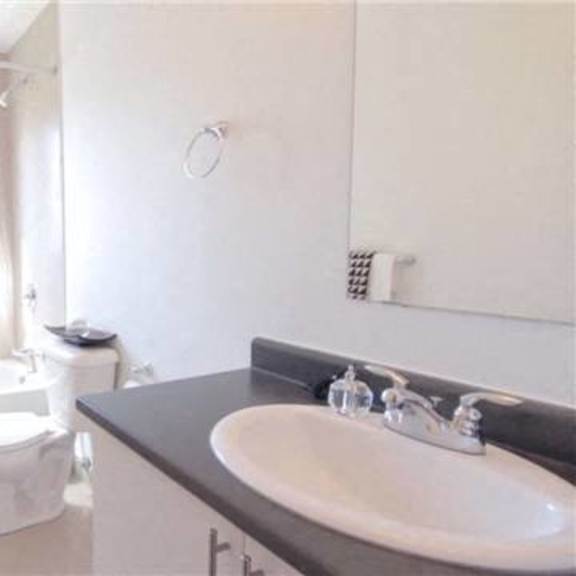 a white bathroom with a toilet, sink, and shower.