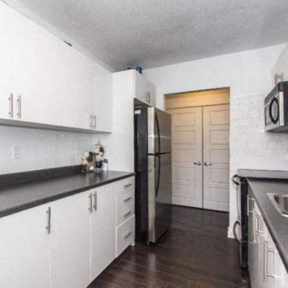a kitchen with white cabinets and a black countertop.