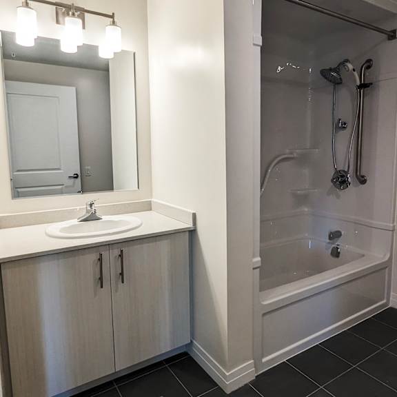 a bathroom with a sink, mirror, and shower.