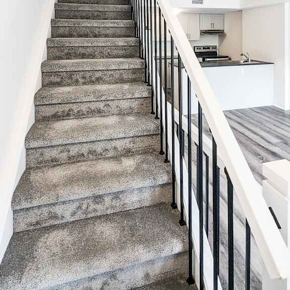 a staircase with a black railing and grey steps.
