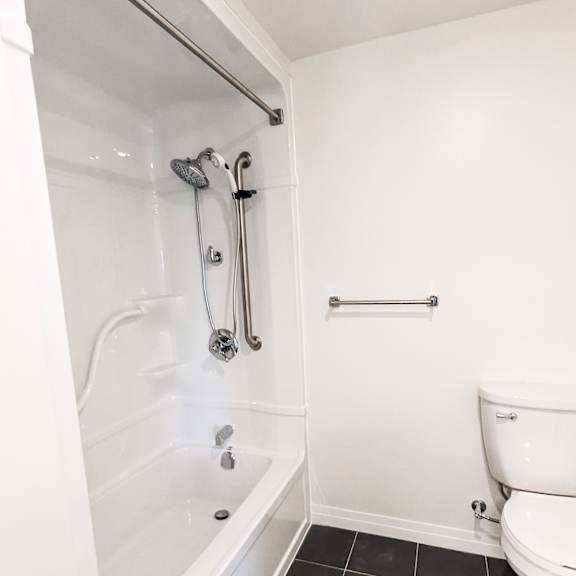 a white bathroom with a toilet and a walk in shower.