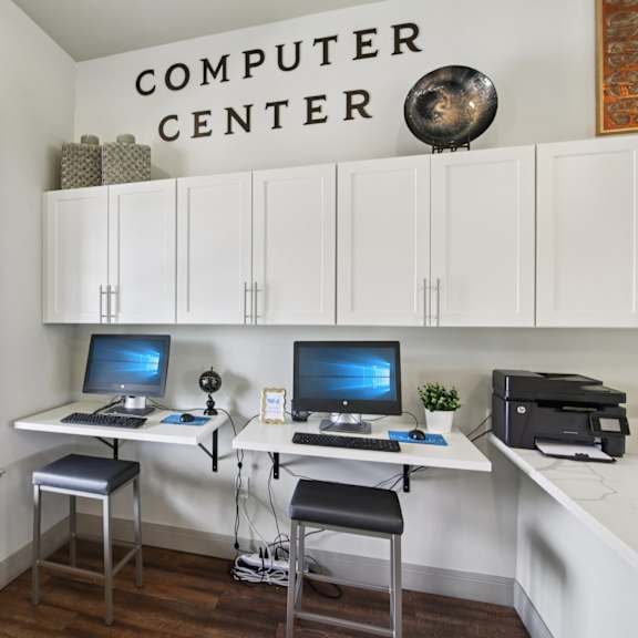 A computer center with two computers and a printer.