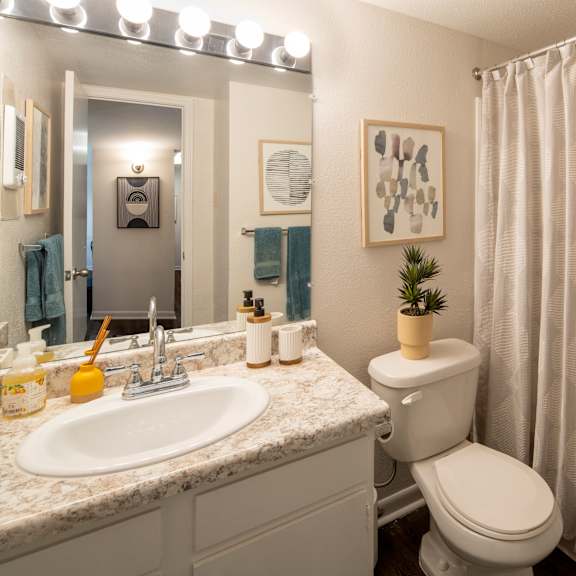 a bathroom with a toilet, sink, and shower.