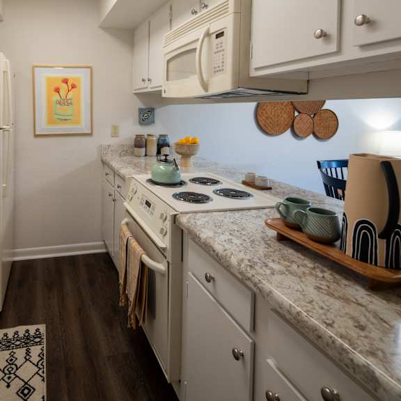 a kitchen with a white fridge, white cabinets, and a white microwave.
