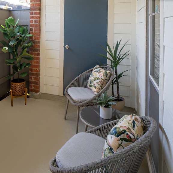 a balcony with a chair and a potted plant.