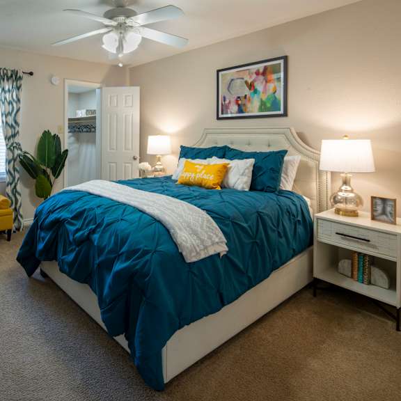 a bedroom with a bed, nightstand, and a ceiling fan.