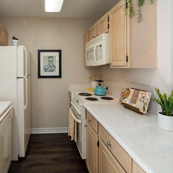 a kitchen with a white fridge, a white microwave, and wooden cabinets.