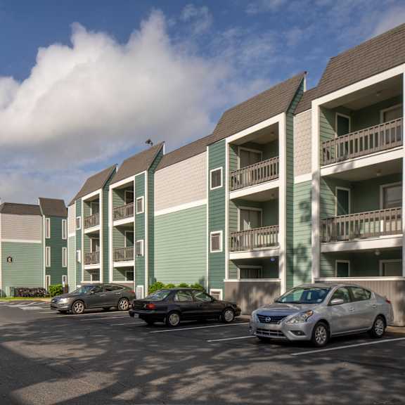 a parking lot with cars and apartment buildings.