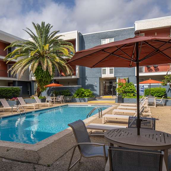 a pool area with chairs and an umbrella.