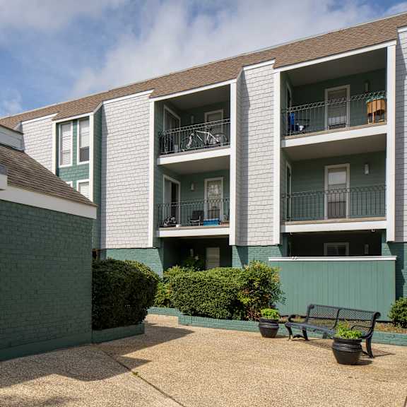 a small house with a grey door is in front of a larger apartment building.