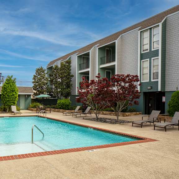 a swimming pool surrounded by a red brick border in a residential area.
