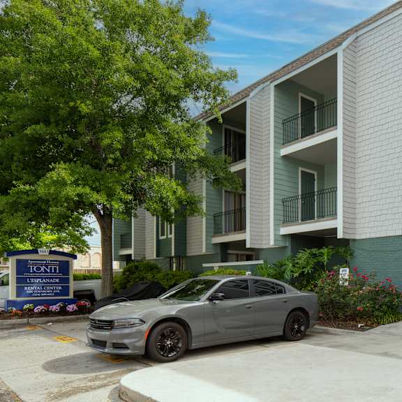 a grey car is parked in front of a building with a blue sign that says "tonini".