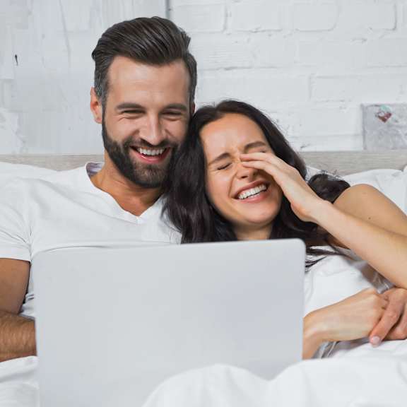couple watching movie on laptop and laughing