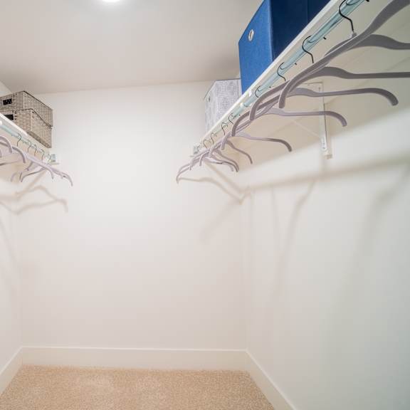 a walk in closet with two shelves and two hanging rails