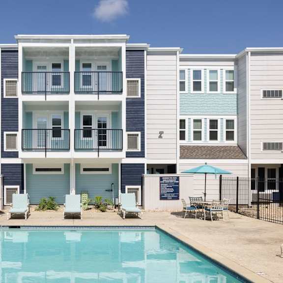 a swimming pool is in front of a row of apartment buildings.