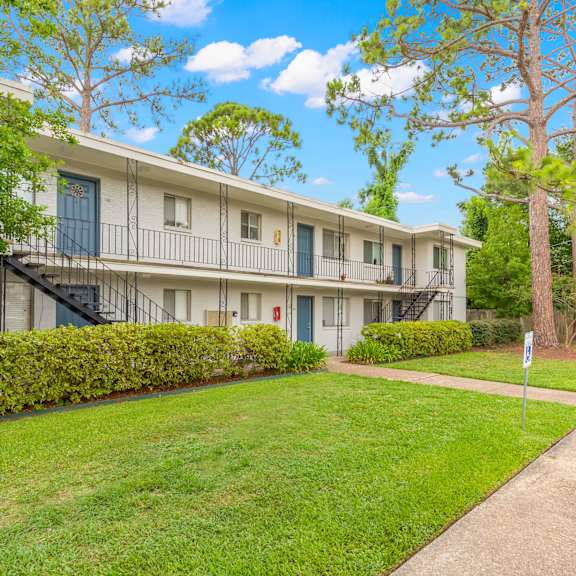 apartment building with green lawn and trees in front.