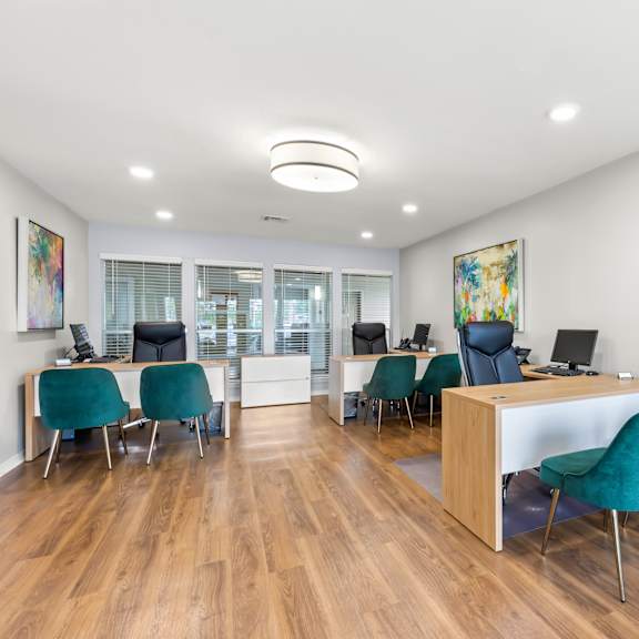 a room with a desk and chairs and a painting on the wall.
