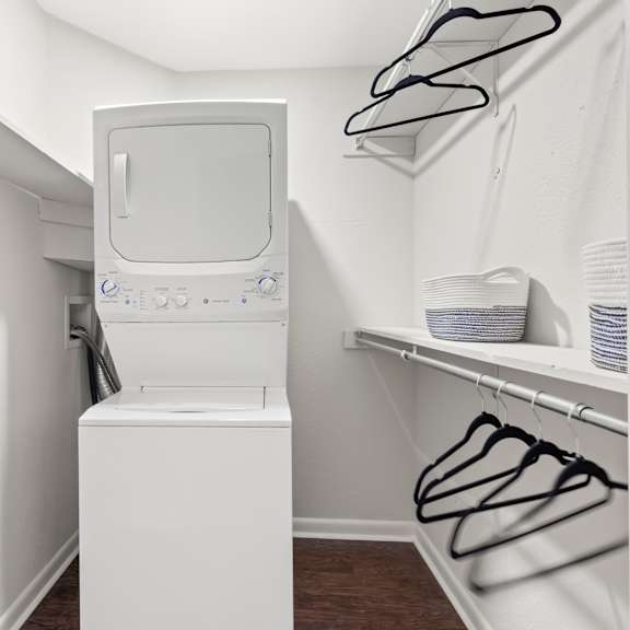 a small white washing machine sits in a laundry room.
