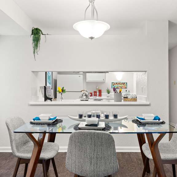 a dining room with a glass table and chairs.