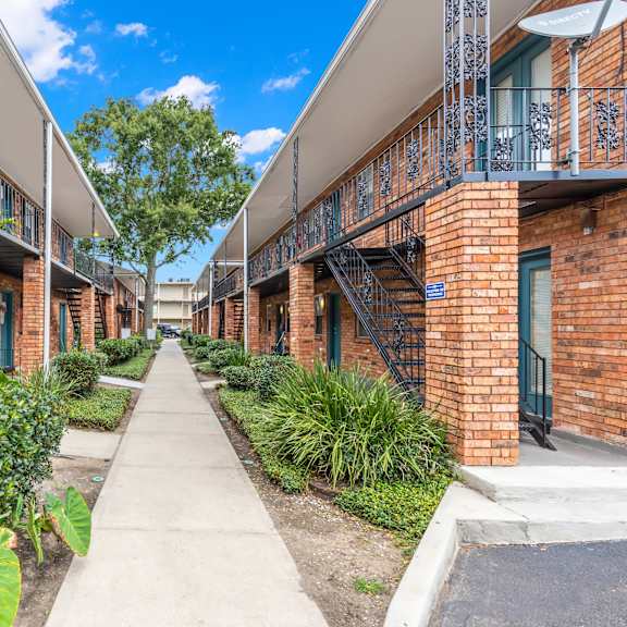 a long, narrow walkway separates rows of red brick apartment buildings.