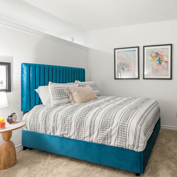 a bedroom with a blue headboard and a white dresser.