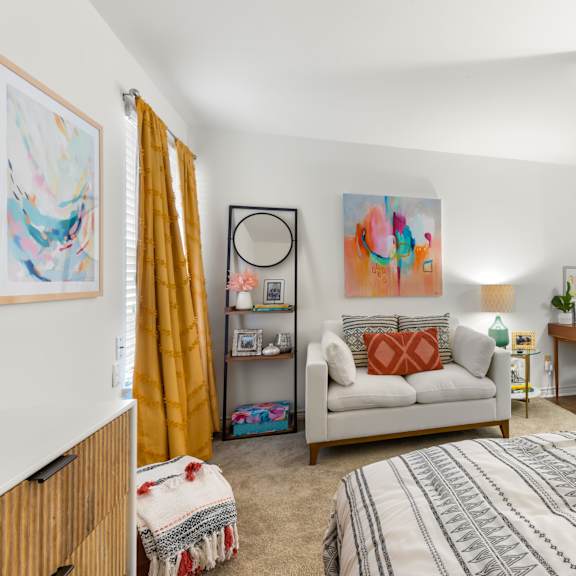 a bedroom with a bed, a couch, a chair, and a painting on the wall.