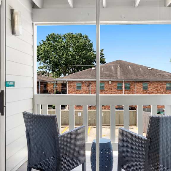 a balcony with chairs and a view of a building.