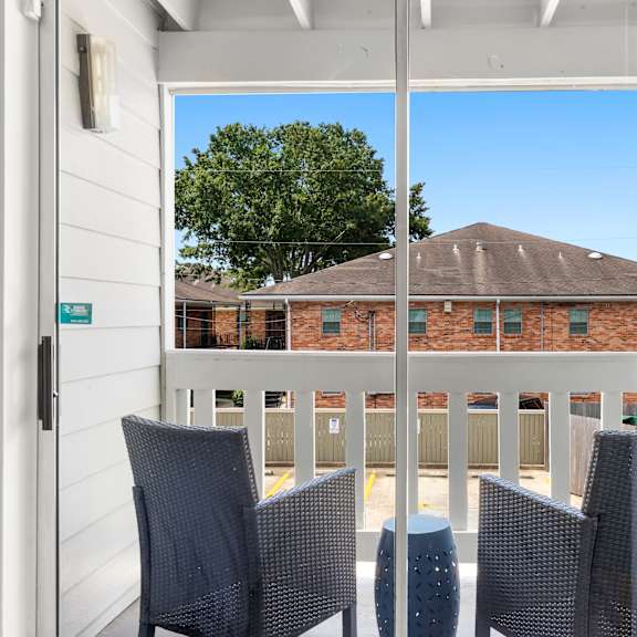 a balcony with chairs and a view of a building.