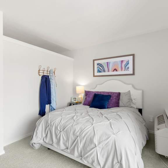 a white bedroom with a white bed and a white shelf with plants on it.