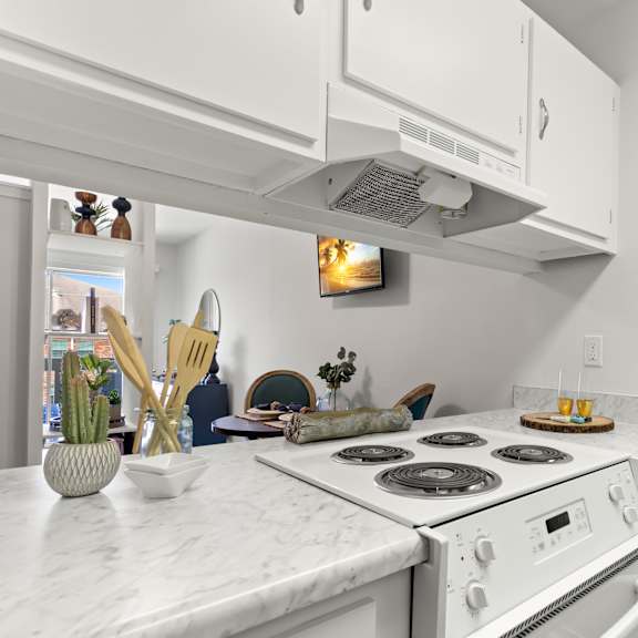 a white kitchen with a stove top oven and a fridge.