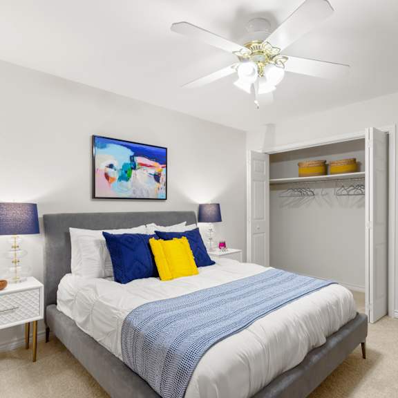 a bedroom with a bed, a ceiling fan, and a painting on the wall.