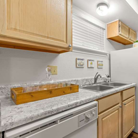 a kitchen with a white fridge, wooden cabinets, and a marble countertop.
