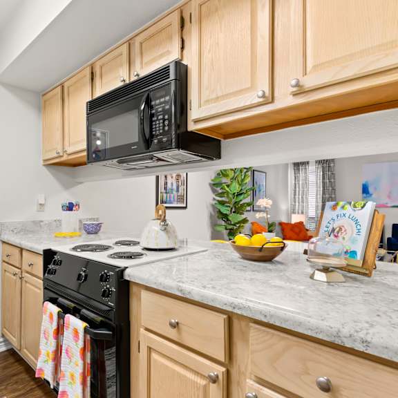 a kitchen with wooden cabinets and a black microwave above the stove.