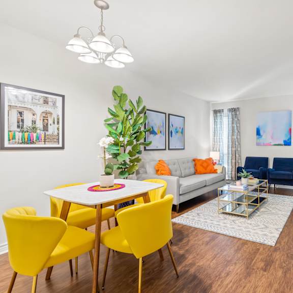 a living room with a white table and yellow chairs.