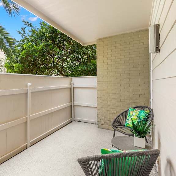 a balcony with a chair and a plant.