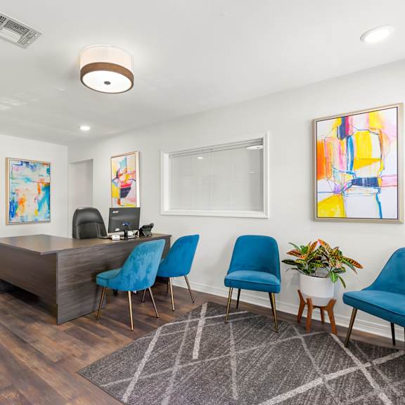 a room with a desk, chairs, and a painting on the wall.