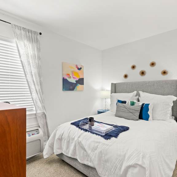 a bedroom with a white bed and a wooden dresser.