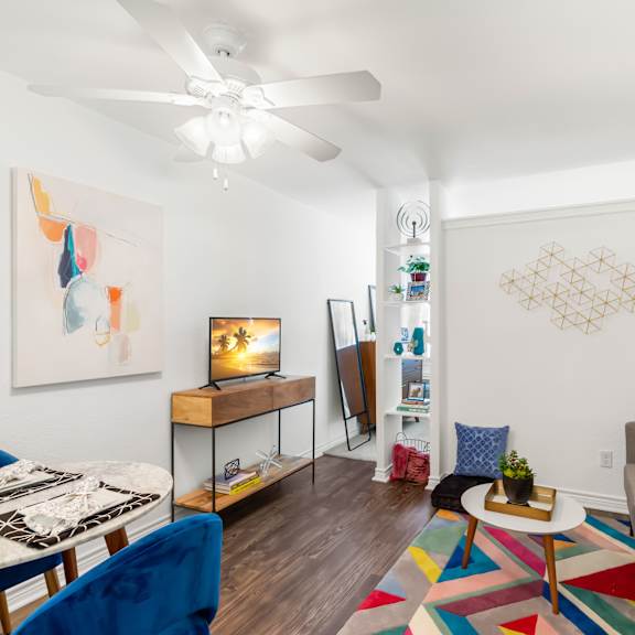 a living room with a white ceiling fan and a painting on the wall.