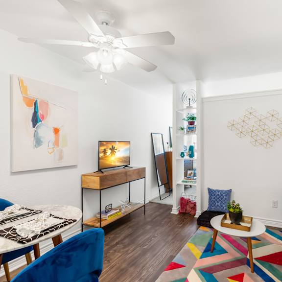 a living room with a white ceiling fan and a painting on the wall.