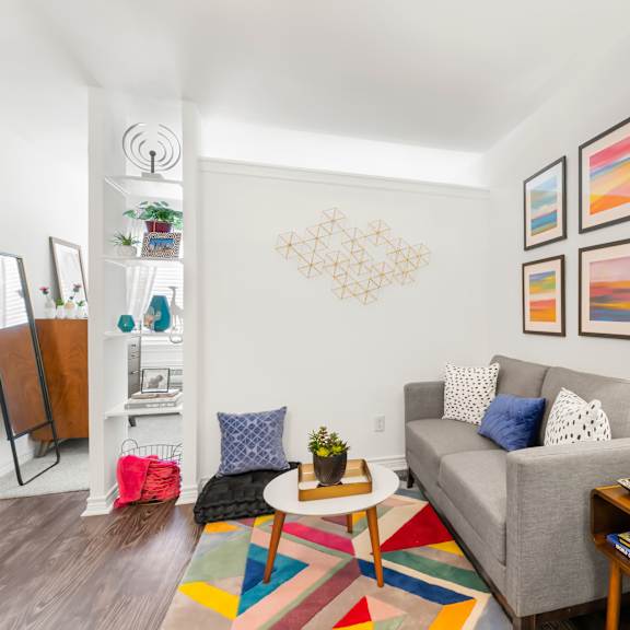 a living room with a grey couch, a coffee table, a lamp, and a bookshelf.