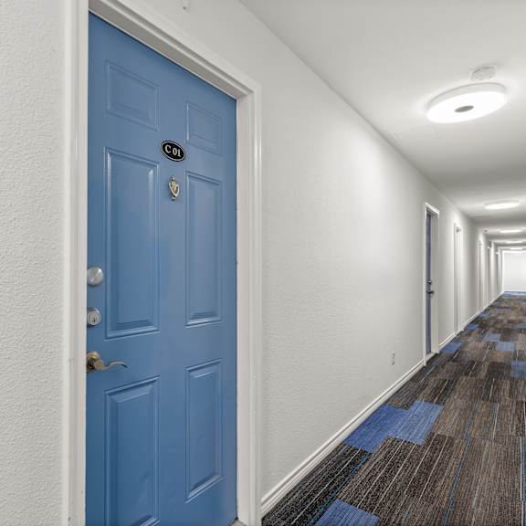 a long hallway with a blue door on the left.