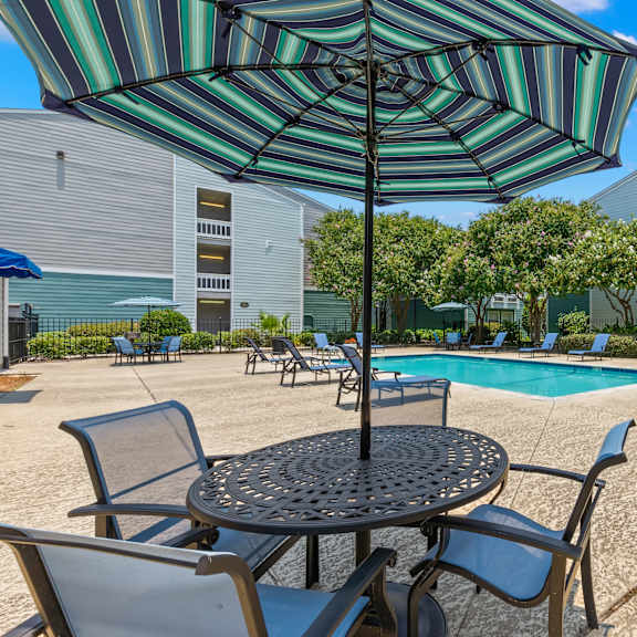 a patio with a table, chairs and an umbrella.