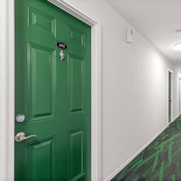 a hallway with a green door and carpet.