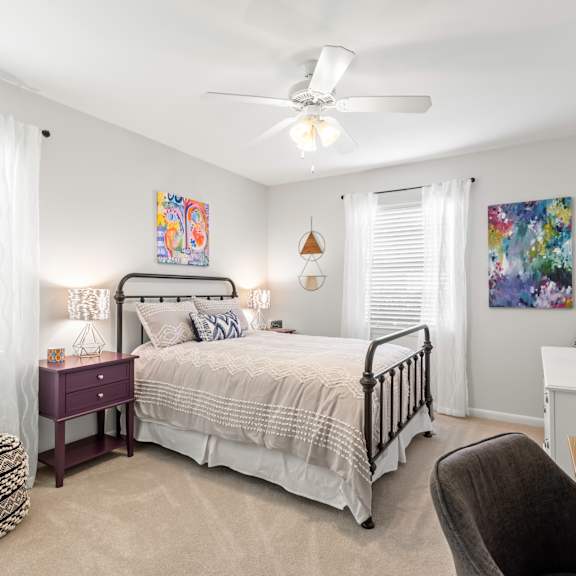 a bedroom with a bed, desk, chair, and a ceiling fan.