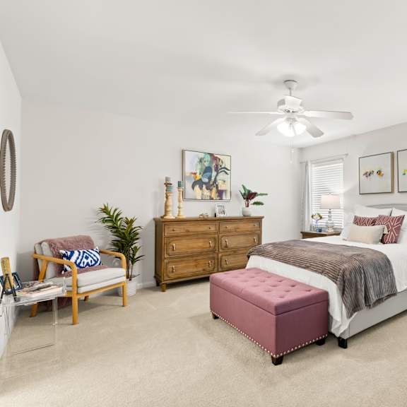 a bedroom with a bed, dresser, and chair.